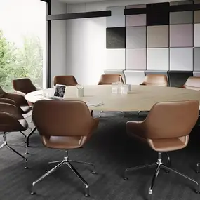 Moderner Konferenzraum mit rundem Holztisch, braunen Bürostühlen und großer Fensterfront mit Ausblick.