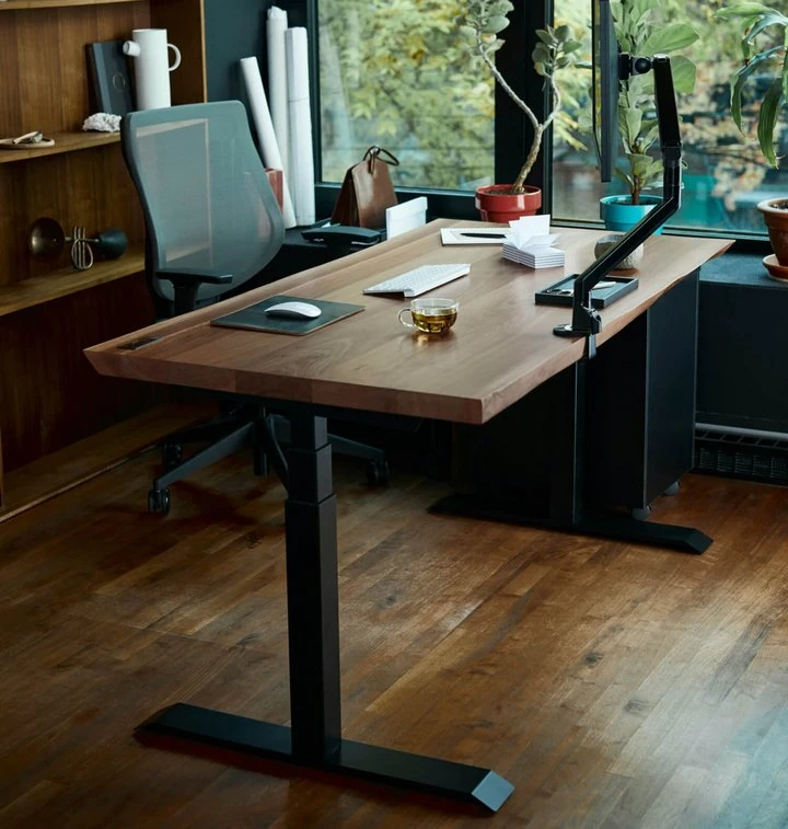 Modernes Home-Office mit höhenverstellbarem Schreibtisch aus Holz und ergonomischem Bürostuhl.